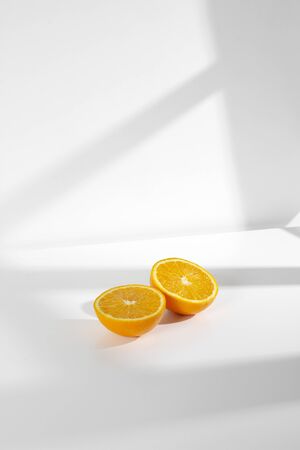 Fresh half oranges with window morning light on white background photographyの写真素材