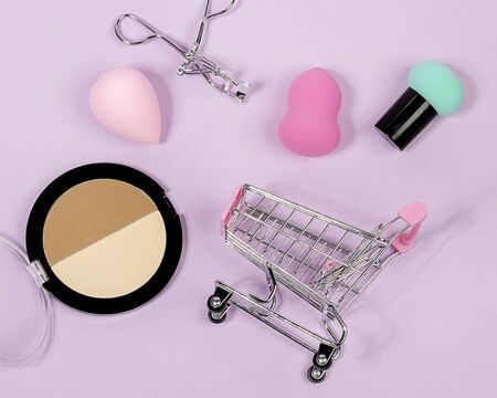 Pastel make-up tool included blender sponge brush powder eyelash curler on purple background