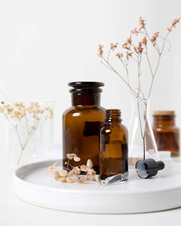Brown serum dropper bottle with relaxing aroma flower and laboratory flask photographyの写真素材
