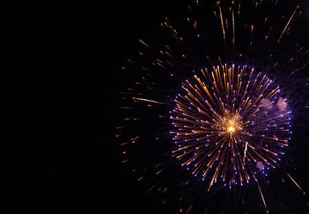 colorful blue and yellow fireworks on an evening night background with space on a side for...