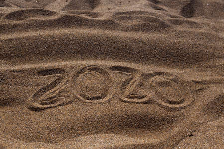 summer 2020 written in the sand with towel flip flops and summer items on sunny dayの写真素材