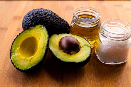 fresh avocado, salt and oil on wooden background closeup