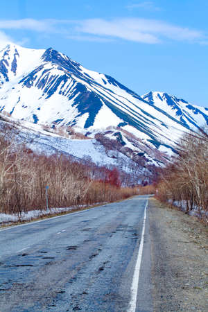 Old asphalt road in the snowy mountains on Kamchatkaの写真素材