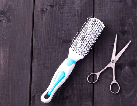 Hairdressing Scissors and massage comb taken from above on a black wooden backdropの写真素材