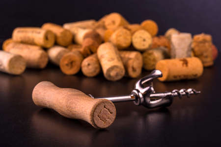 Wine corks and corkscrew on black wooden tableの写真素材