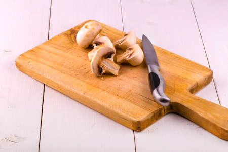 Champignons on a wooden board and a table knifeの写真素材