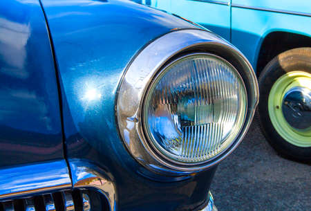 Blue vintage car on a festival of old cars. Retro car's headlight close up.の写真素材