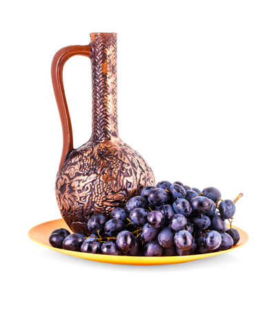 Blue grapes and clay jug on white backgroundの写真素材