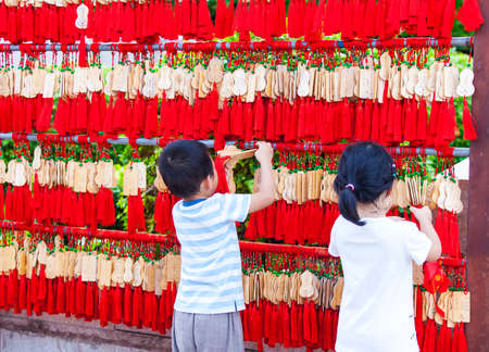 China, Sanya - 15 Nov 2017: Chinese children hang EMA in a Buddhist templeのeditorial素材