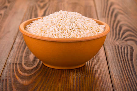 raw white rice in a Cup on a wooden tableの写真素材