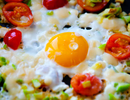 Freshly made scrambled eggs with tomatoes in a pan, close upの写真素材