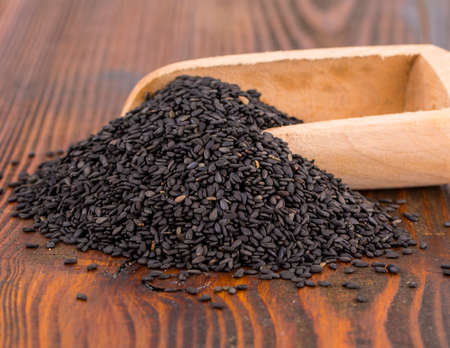 black sesame in spoon on wooden surface