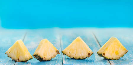 Spring or summer concept : Close up patter of many pieces of yellow pineapple  on blue wooden table background.の写真素材
