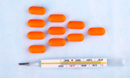 The pills in red packaging and thermometer on blur medical backgroundの写真素材