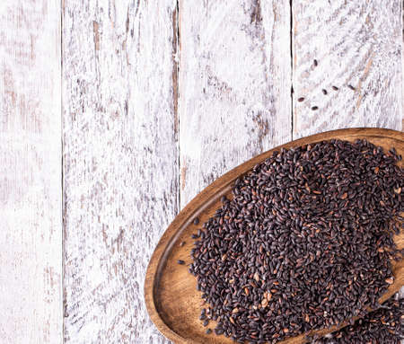 Wooden plate with black rice on old wooden backgroundの写真素材