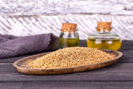 Sesame oil in glass and seeds on wooden backgroundの写真素材