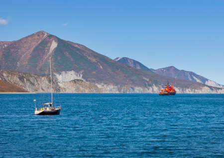 The Kamchatka peninsula. Pacific coast. Sailing yacht and red ship in the bay. Selective focus