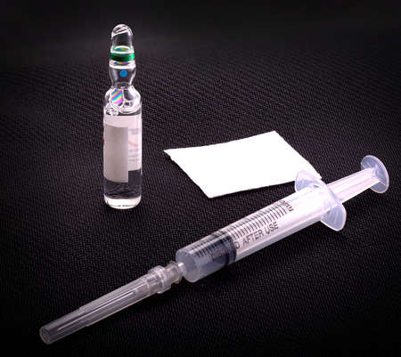 Medical syringe and glass vial on a black background.の写真素材