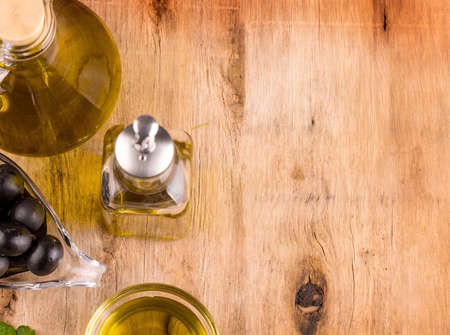 Olive oil with fresh herbs and Black olives on woodenの写真素材