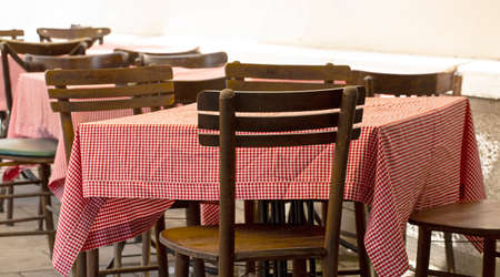 outdoor cafe tables and chairs with a red tableclothの写真素材