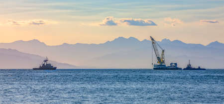 sea ship with a crane on the background of a mountain range in the hazeの写真素材