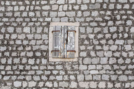 old house stone wall, with cracked window shutters in light wood