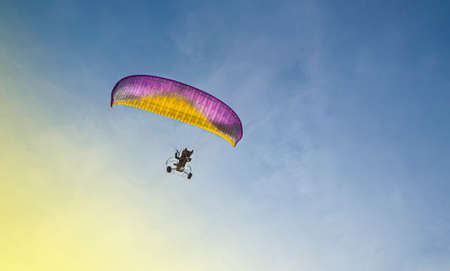 paraglider with a motor flies in the blue skyの写真素材