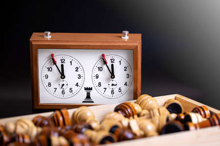 Chess pieces on a board and a chess clock on a dark backgroundの写真素材