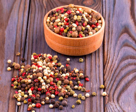 peppers on wooden backround with wooden cup and round black pepper