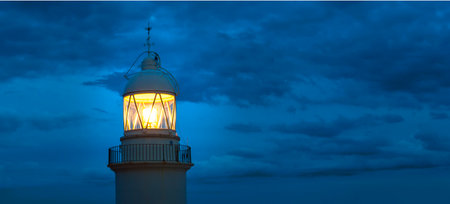 Lighthouse glowing at dark night on coast Spainの写真素材