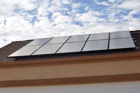 Solar Panel on Roof of New Home with Clouds and Blue Skyの写真素材