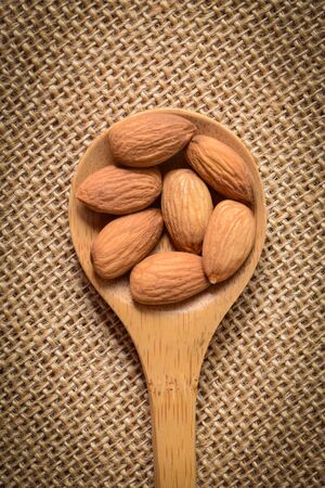 Almonds in a Wodden Spoon on a Burlap Backgroundの写真素材