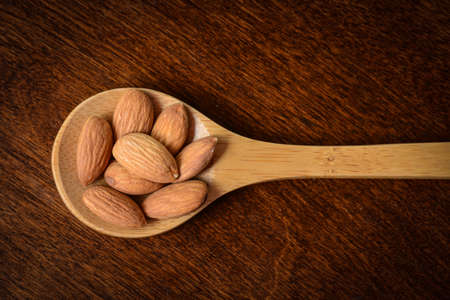 Almonds on a Wooden Spoon with Wood Texture Backgroundの写真素材