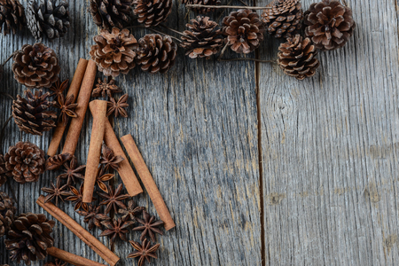 Cinnamon sticks, star anise and pine cones on rustic wood backgroundの写真素材
