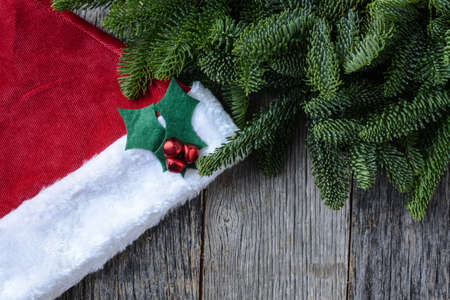 Pine Tree Branches and Santa Hat on Rustic Wood Backgroundの写真素材