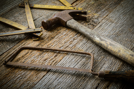 Hammer, Saw and Measuring Tape on Rustic Wood Backgroundの写真素材