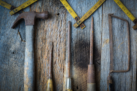 Hammer, Screwdriver, Hand Saw and Tape Measure on Rustic Wood Backgroundの写真素材