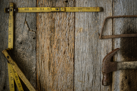 Measuring Tape Hammer and Saw on Rustic Old Wood Backgroundの写真素材