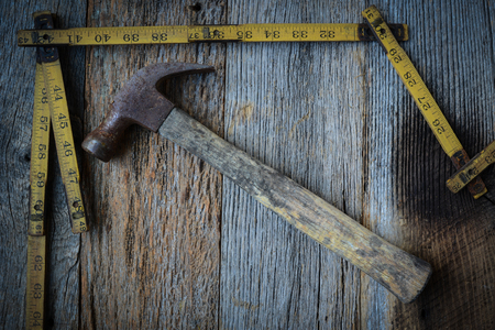 Old Tape Measure and Hammer for Construction on Rustic Wood Backgroundの写真素材