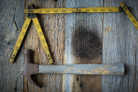 Old Tape Measure and Hammer for Construction on Rustic Wood Backgroundの写真素材