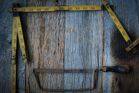 Old Tape Measure and Saw for Construction on Rustic Wood Backgroundの写真素材