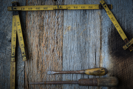Old Tape Measure and Screwdriver for Construction on Rustic Wood Backgroundの写真素材