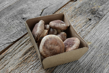 Shitake Mushroom in Cardboard Packaging on Wood Backgroundの写真素材