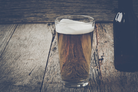 pint of pilsner beer on wood background with vintagefilm styleの写真素材