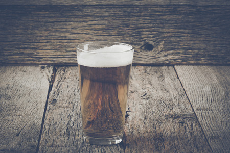 pint of pilsner beer on wood background with vintage film styleの写真素材