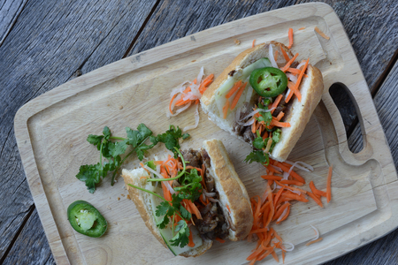 Vietnamese Grilled Pork Banh Mi Sandwich on Rustic Wood Backgroundの写真素材