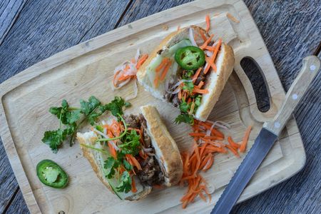 Vietnamese Grilled Pork Banh Mi Sandwich on Rustic Wood Backgroundの写真素材