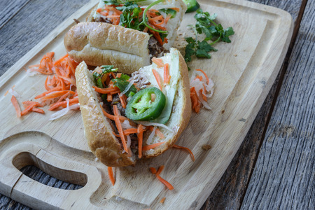 Vietnamese Grilled Pork Banh Mi Sandwich on Rustic Wood Backgroundの写真素材
