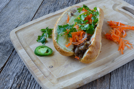 Vietnamese Grilled Pork Banh Mi Sandwich on Rustic Wood Backgroundの写真素材