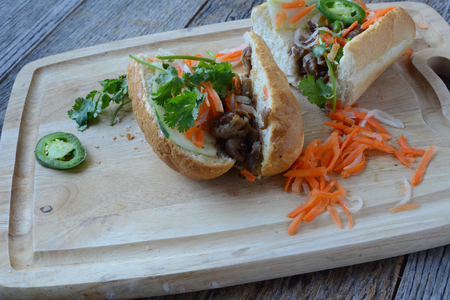 Vietnamese Grilled Pork Banh Mi Sandwich on Rustic Wood Backgroundの写真素材
